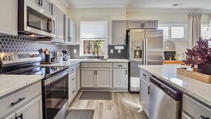 A modern kitchen with stainless steel appliances, a microwave, and a water dispenser. - Beautifully Renovated Historic 4 BR Home|Sleeps 16 (Birmingham)