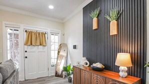 A modern living room with a wooden cabinet, a mirror, and a lamp. - Beautifully Renovated Historic 4 BR Home|Sleeps 16 (Birmingham)