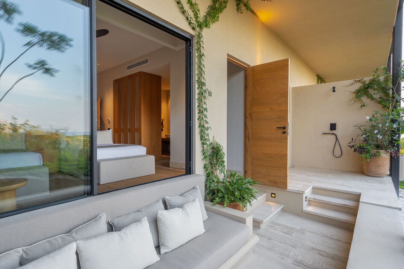 Ein modernes Interieur mit einer Glaswand, einem Sofa, einer Holztür und einem Blumentopf.