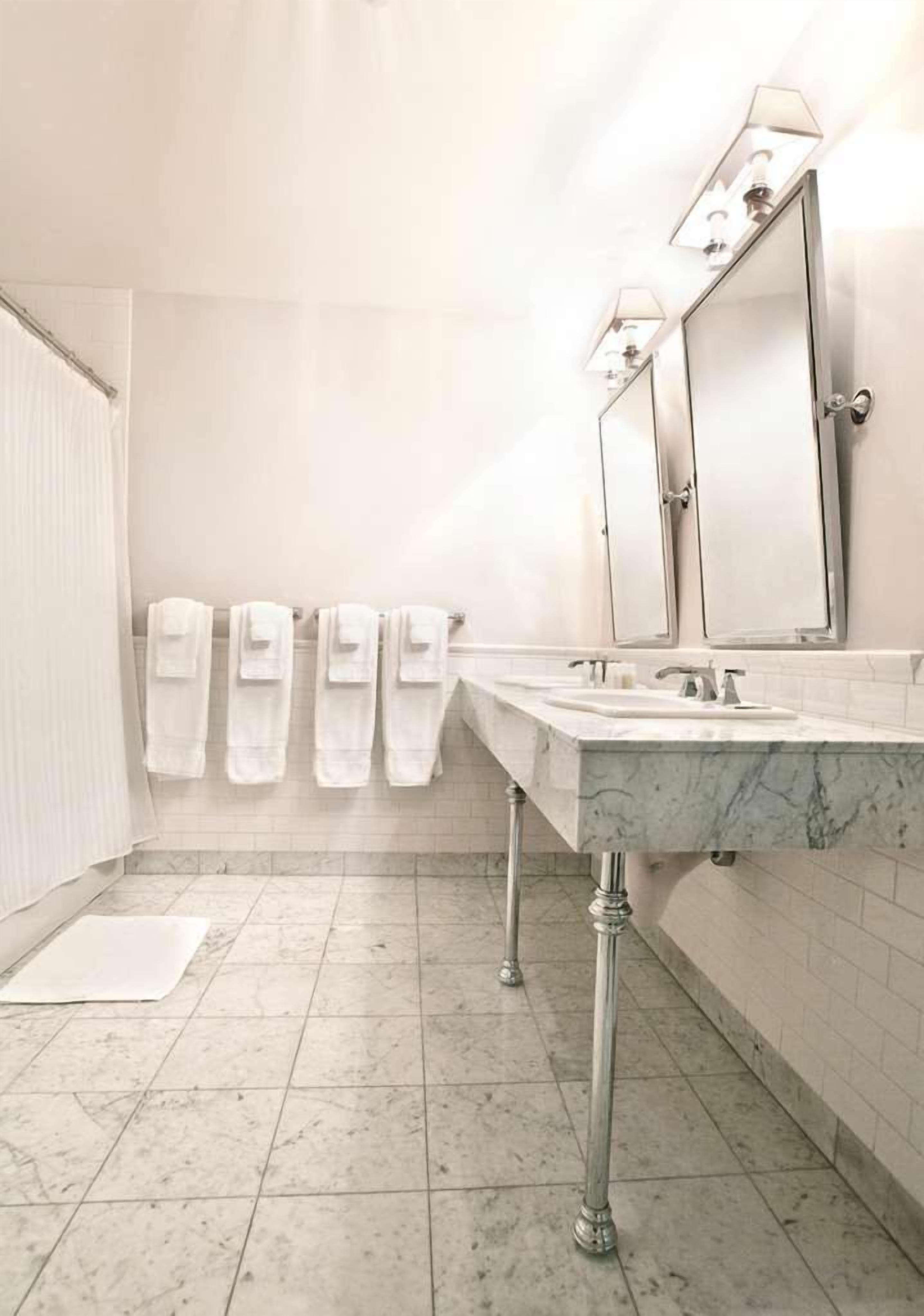 A bathroom with two sinks, a mirror, and a towel rack with multiple towels.