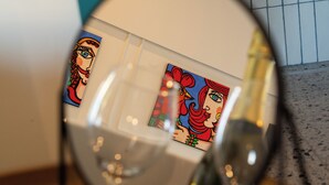 Un gros plan d’un objet en verre qui reflète une œuvre d’art sur un mur.
