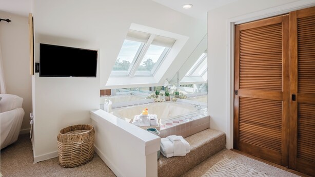 Un bagno moderno con una vasca freestanding, uno specchio ampio e un lucernario.