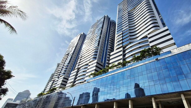 A modern high-rise building with a reflective glass facade, multiple balconies, and a clear sky. - COCAR0115 - Salvador Prime (Salvador)