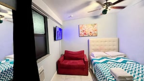 A bedroom with a bed, a red chair, a ceiling fan, a TV, and a painting on the wall. - Wonderful 1-bedroom backyard in Fort Lauderdale (Fort Lauderdale)