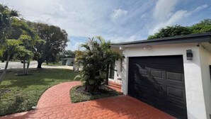 A residential driveway with a hexagonal patterned walkway leading to a garage. - Wonderful 1-bedroom backyard in Fort Lauderdale (Fort Lauderdale)