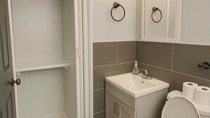 A bathroom with a toilet, sink, and mirror. There is a black bath mat on the floor. - Wonderful 1-bedroom backyard in Fort Lauderdale (Fort Lauderdale)