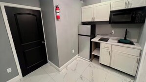 A compact kitchen with white cabinets, a black refrigerator, and a black microwave. - Wonderful 1-bedroom backyard in Fort Lauderdale (Fort Lauderdale)