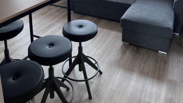 A modern interior with a grey sectional sofa, a wooden dining table, and black stools. - Kot apartment (Hvolsvöllur)