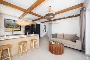 Una cucina moderna con travi in legno, un angolo bar con sgabelli, un tavolino rotondo in legno e un divano in salotto.