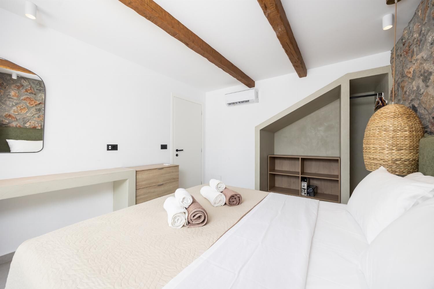 A hotel room with a bed, a desk, a wardrobe, and a hanging basket.