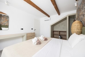 A hotel room with a bed, a desk, a wardrobe, and a hanging basket. - Villa Serenita - Two Bedroom Villa, Sleeps 4 (Afandou)