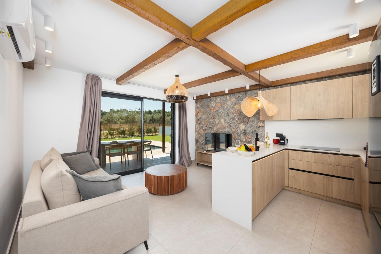 Une cuisine moderne avec un mur de crédence en pierre, des armoires en bois et un coin repas comprenant une table et des chaises en bois, le tout de forme ronde.