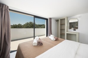 A hotel room with a large window, a bed with rolled towels, a mirror, and a wardrobe. - Villa Celestia - Two Bedroom Villa, Sleeps 4 (Afandou)