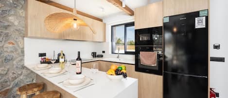 Una cocina moderna con una isla grande, detalles de madera y un refrigerador negro.