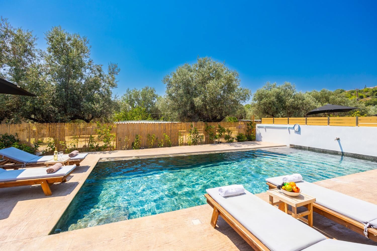 Une piscine aux eaux cristallines, dotée de chaises longues et d’une terrasse en bois.