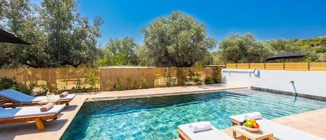 Ein klarer Pool mit Liegestühlen und einer Holzterrasse.