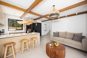 Eine moderne Küche mit Holzbalken, einer Bar und einem Wohnbereich mit Sofa und Couchtisch.