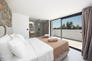 Ein modernes Schlafzimmer mit einem großen Bett, einer integrierten Dusche und einem Balkon mit Blick.