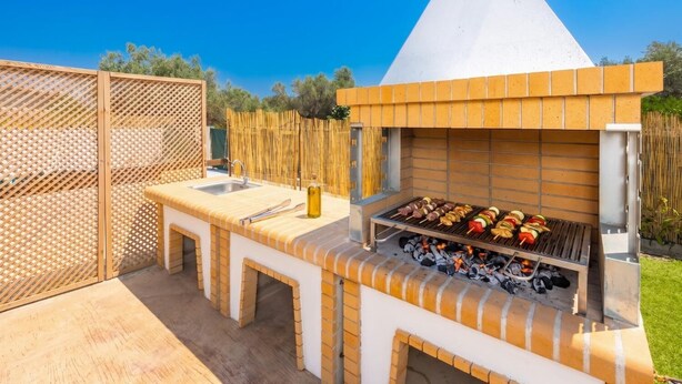 En utomhusplats för grillning med en grill, ett handfat och en flaska olja.