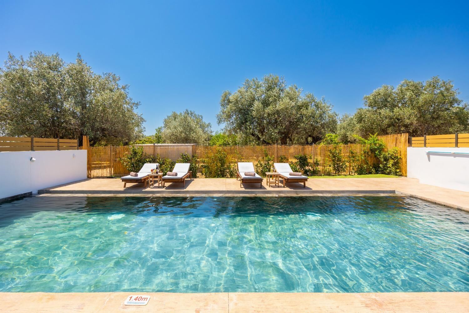 Une piscine aux eaux cristallines, dotée de chaises longues et d’une terrasse en bois.