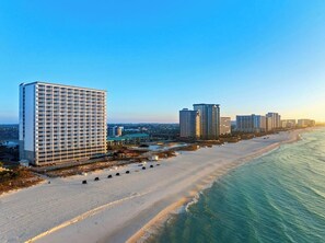 A beachfront hotel with multiple high-rise buildings, a sandy beach, and a clear view of the ocean. - Pelican Beach Resort · Ocean Views | 3 Pools, Hot Tub, Courts, Gym & Balcony (Destin)