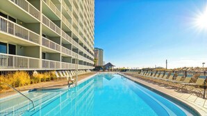 Une piscine à l’eau d’un bleu cristallin, entourée d’une terrasse en bois et de chaises longues.