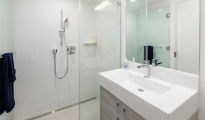 Een moderne badkamer met een douchecabine van glas, een wit wastafelmeubel en een grote spiegel.