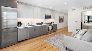 A modern kitchen with grey cabinets, stainless steel appliances, a microwave, and a coffee maker.