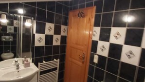 A bathroom with black and white checkered tiles, a wooden door, a white sink, and a small cabinet. - Pansion Dovodja - Close to the beach and the center - your vacation home / Apartment 9 (Vodice)