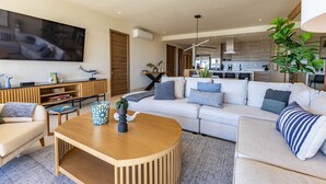A modern living room with a large flat-screen TV, a wooden coffee table, and a beige sofa. - Vista Del Arco - Vista Vela Sunset (Cabo San Lucas)