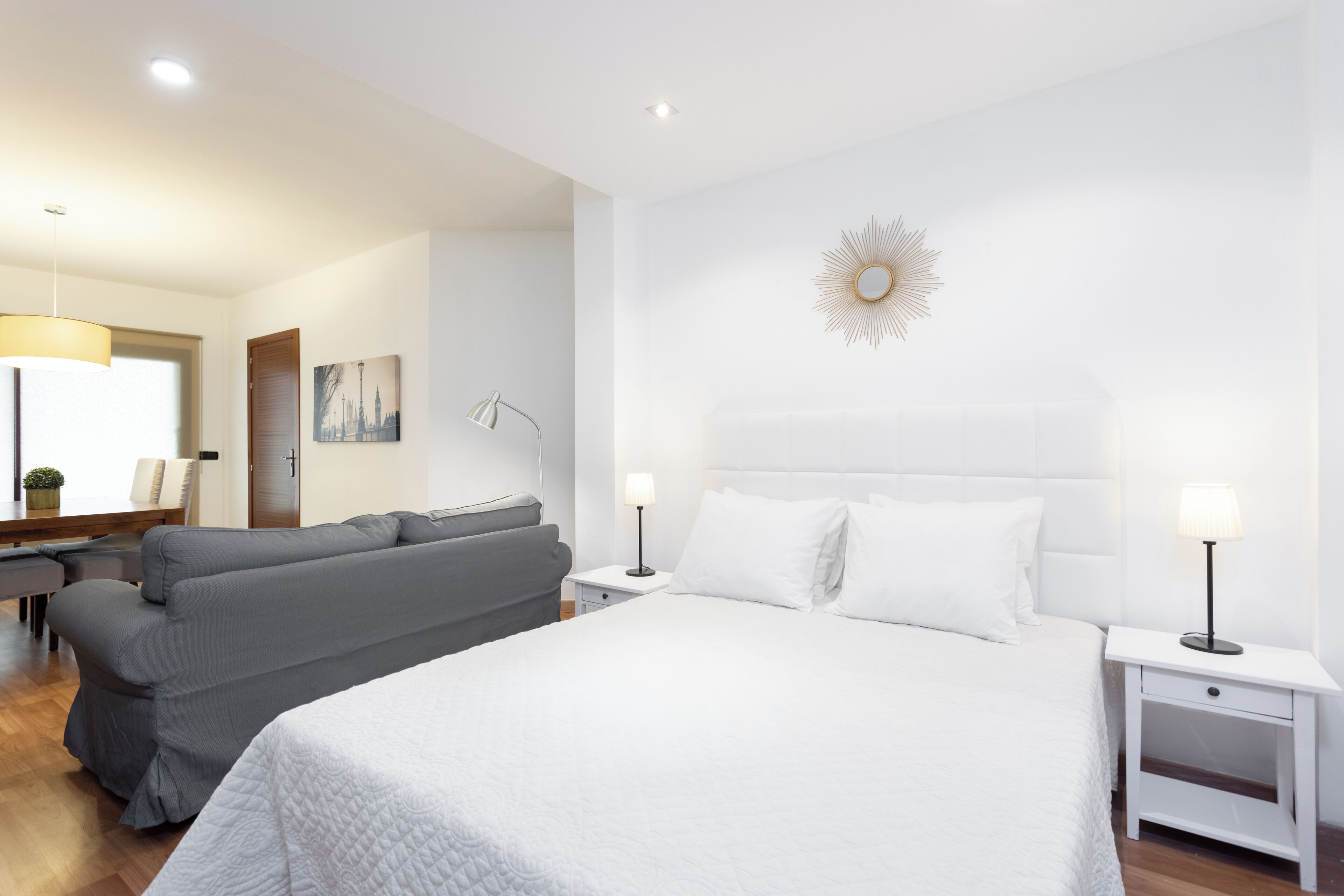 Ett modernt hotellrum med en stor säng, en grå soffa, ett skrivbord och en lampa.
