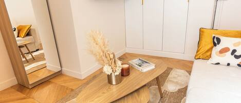 Une chambre à coucher avec un lit, une table de chevet en bois, un miroir, une télévision et une porte.