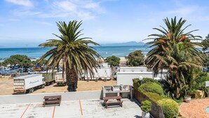 A view of a beachside area with palm trees, a parking lot, and a beach in the background.