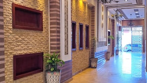 A hallway with patterned walls, recessed lighting, and a potted plant. - Abraj Dubai - Luxury LovelyStay (Larache)