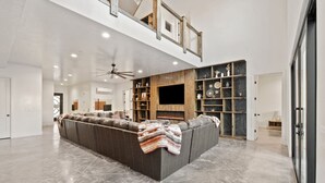 Un'ampia zona giorno con un grande divano ad angolo, un camino e un soffitto alto con travi a vista.