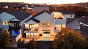 Una moderna casa a due piani con un balcone, una piscina e un esterno luminoso.