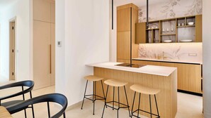 Una cucina moderna con isola centrale, sgabelli da bar, mobili in legno e una decorativa schiena di cucina.