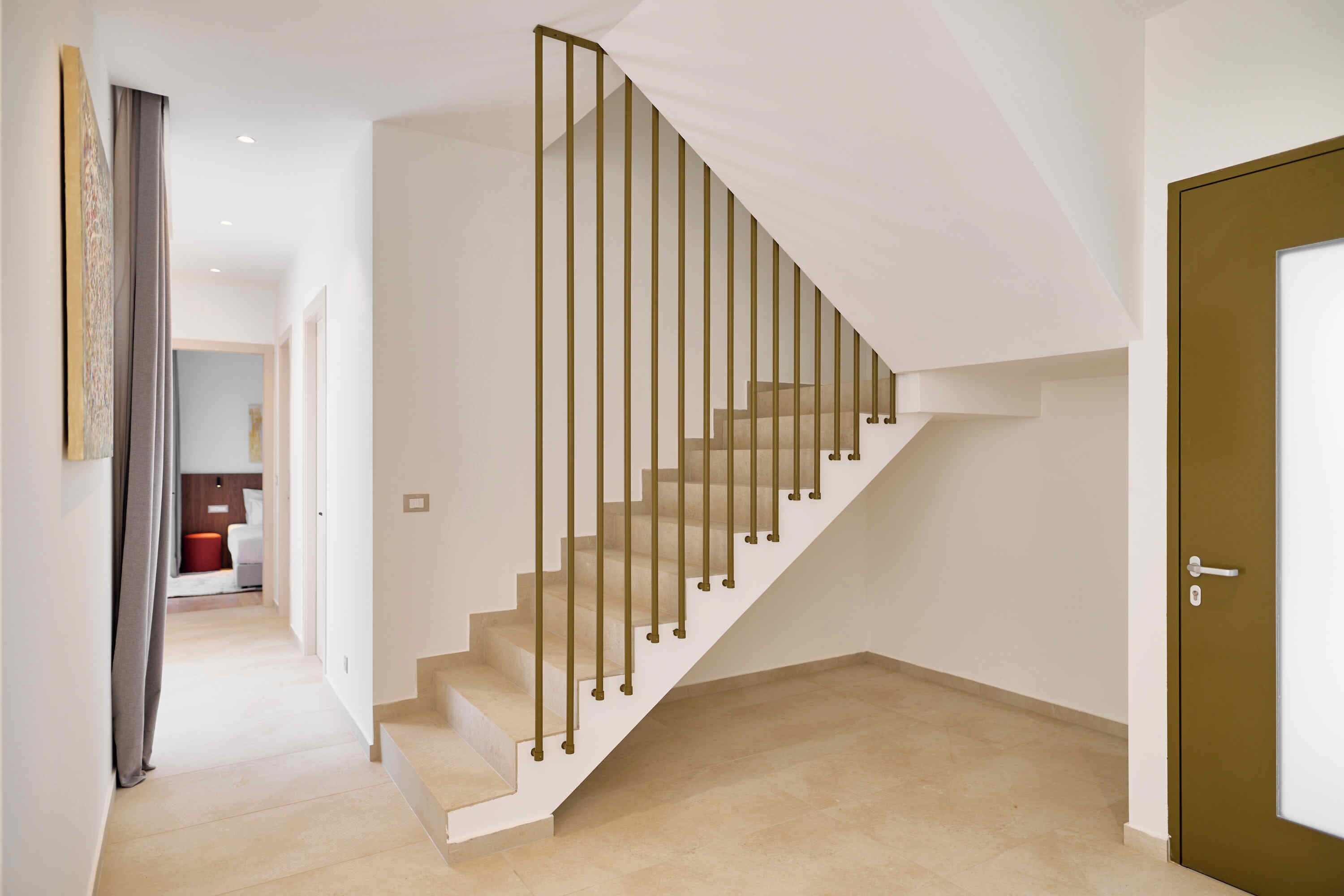A modern staircase with a minimalist design, leading to a room with a door and a light-colored floor.