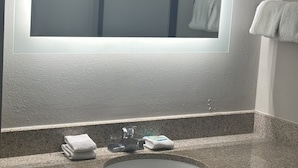 Un baño con encimera de granito, un lavabo y un espejo.