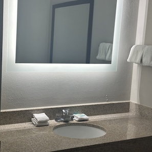 Un baño con encimera de granito, un lavabo y un espejo.