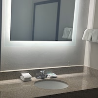 Un baño con encimera de granito, un lavabo y un espejo.