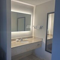 A bathroom with a granite countertop, a sink, a mirror, and a towel rack.