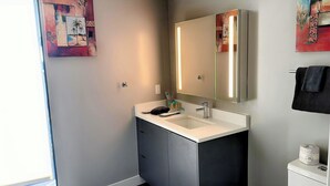 A modern bathroom with a white sink, dark cabinets, and a large mirror.