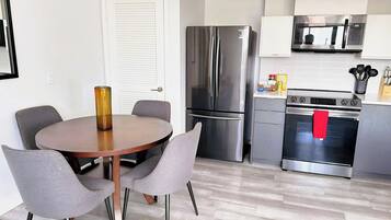A modern kitchen with stainless steel appliances, a dining table with chairs, and a microwave above the stove.