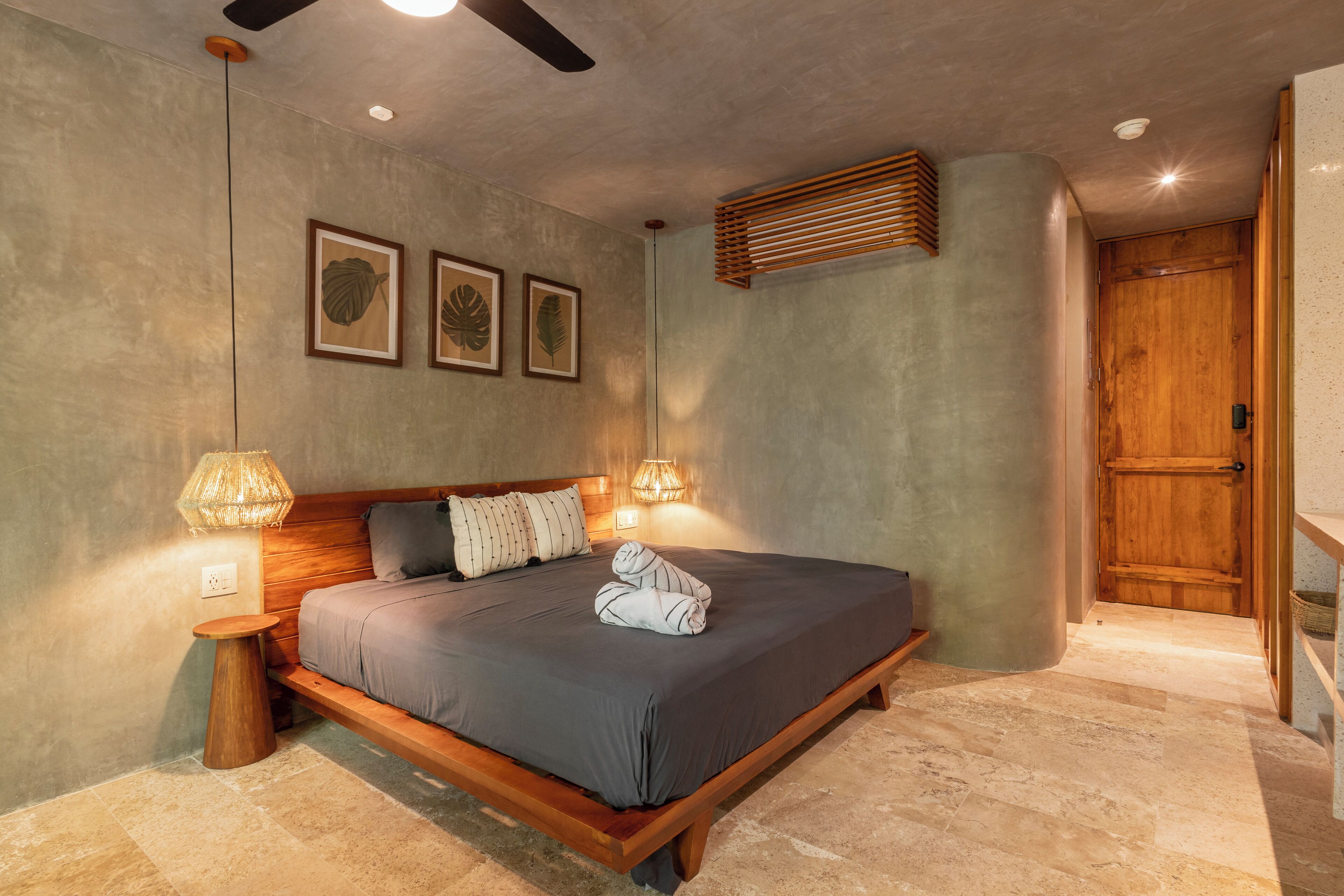 A bedroom with a wooden bed, a nightstand, a lamp, and framed pictures on the wall.