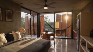 A modern bedroom with a large bed, a dining table, and a balcony with a view. - Seremonia Origen (Tulum)