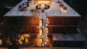 A modern house with a spiral staircase, outdoor seating, and a central fire feature. - Seremonia Origen (Tulum)