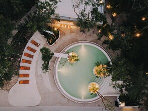 A circular pool with seating around it, surrounded by trees and a pathway. - Seremonia Origen (Tulum)