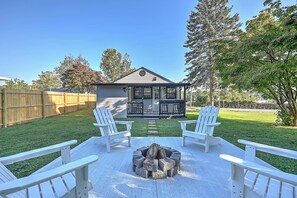 Un jardin avec un foyer, deux fauteuils Adirondack et une terrasse en bois.
