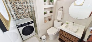 Een kleine badkamer met een wasmachine, toilet, wastafel en een spiegel.